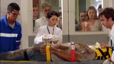 Ester, Duque e os tenentes observam pelo janela do ambulatório Cassiano  na maca, inconsciente  