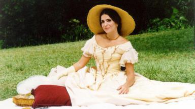 Malu Mader caracterizada como a Baronesa de Sobral, sentada num jardim, numa espécie de piquenique 