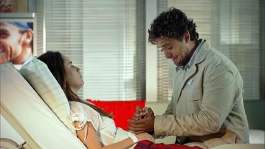 Cena de A Vida da Gente com Rodrigo segurando a mão de Ana, que está deitada, e chorando 