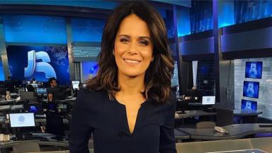 Adriana Araújo sorri à frente da bancada do Jornal da Record 
