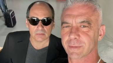 Enio Martins Murad e Alexandre Correa posando para selfie sérios, o primeiro de óculos escuros 