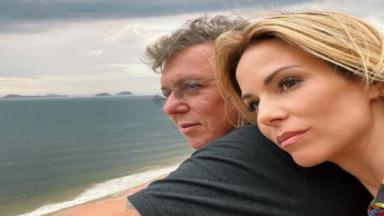 Boninho e Ana Furtado posam em sacada em frente ao mar  