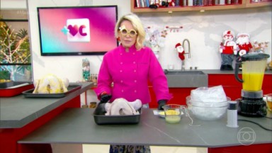 Ana Maria Braga na bancada da cozinha do Mais Você, com roupa de chef cor de rosa 