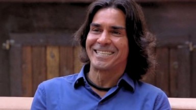 André Gonçalves sorrindo de camisa azul e cabelo solto 