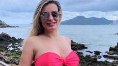 Andressa Urach posada de biquíni e óculos em uma praia 