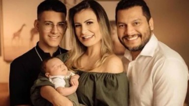Andressa Urach posada sorridente com filho caçula no colo, filho adolescente e marido 