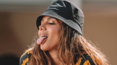 Anitta posada de perfil mostrando a língua 