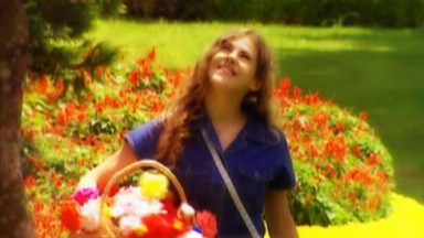 Marisol, personagem de Bárbara Paz, com uma cesta de flores de papel, sorrindo e olhando para cima 