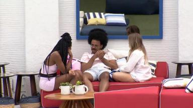 Camilla de Lucas, João Luiz e Carla Diaz sentados conversando na área externa do BBB21 