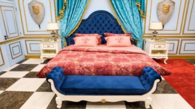 Imagem do guardo do líder pegando a cama de casal com a colcha vermelha e detalhes da parede em azul 