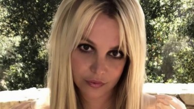 Britney Spears posando pra câmera com fundo cheio de árvores 