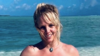 Britney Spears sorrindo e mar azul ao fundo 