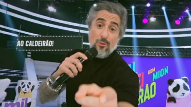 Marcos Mion apontando o dedo para a tela da Globo 