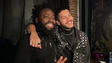 Douglas Silva e Arthur Aguiar posando para foto abraçados e sorrindo, de roupas pretas 