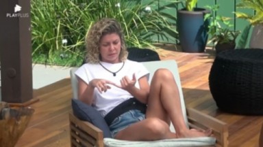 Bárbara Borges de short jeans e camiseta branca sentada na área externa de A Fazenda 2022 