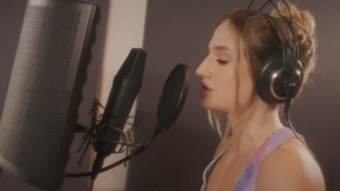 Bruna Griphao de perfil, cantando em microfone de estúdio 