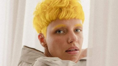 Bruna Linzmeyer de roupa bege, sem sorrir e com cabelo e sobrancelhas amarelos 