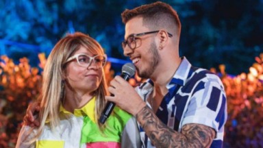 Marília Mendonça e João Gustavo se olhando e sorrindo em palco 