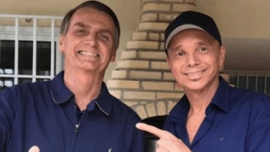 Jair Bolsonaro (PL) e Netinho de camisas azuis e sorrindo 
