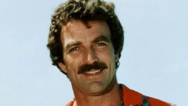 Tom Selleck de camisa florida, sorrindo, em foto de década de 1980 