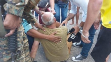 Repórter cinematográfico da InterTV no chão após ser agredido, cercado de pessoas 