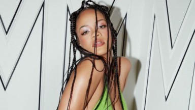 Rihanna de roupa verde e cabelos trançados, posando para foto sem sorrir 