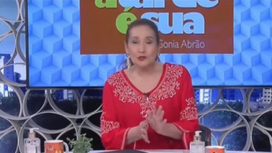 Sonia Abrão falando e gesticulando, de blusa vermelha e rabo de cavalo 