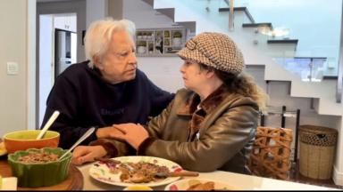 Cid Moreira e a mulher, Fátima Sampaio, sentando em uma mesa olhando um para o outro 
