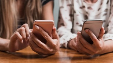 Pessoas mexendo em celular; cyberbullying é crime 