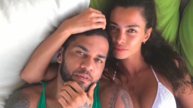 Daniel Alves e Joana Sanz posam abraçados e deitados 