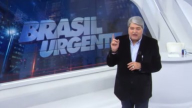 Datena de terno preto e camisa azul clara falando no cenário do Brasil Urgente 