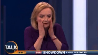 Liz Strass com a mão no rosto, chocada com queda de apresentadora no debate 