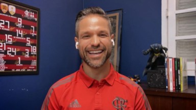 Diego Ribas com camisa do Flamengo, sorrindo, de fones de ouvido sem fio 