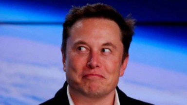 Elon Musk olhando de rabo de olho e rindo como o Coringa 