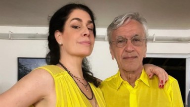 Paula Lavigne e Caetano Veloso posando abraçados, de roupas amarelas 