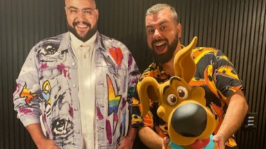 Fernando Poli posando para foto com totem de Tiago Abravanel e um boneco do Scooby-Doo 