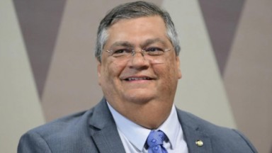 O Ministro da Justiça sorrindo usando paletó e gravata azul 