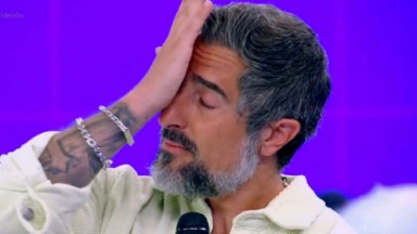 Marcos Mion chorando segurando microfone 