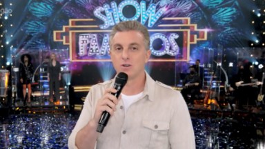 Luciano Huck segurando microfone no palco do Domingão da Globo 