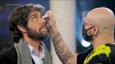 Thiago Arancam recebendo um colírio nos olhos de um colaborador do Domingão 
