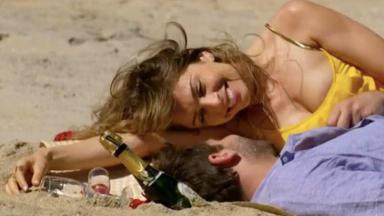 Ester e Cassiano deitados na areia da praia  