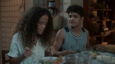Gabriel Santana e Aline Borges como Renato e Zuleica na novela Pantanal. Os dois estão jantando 