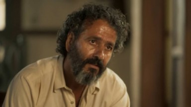 Marcos Palmeira como José Leôncio em Pantanal. Ele está sentado na sala da sua fazenda 