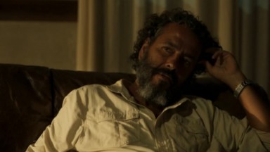 Marcos Palmeira como José Leôncio em Pantanal. Ele está sentado na cadeira da sua sala 