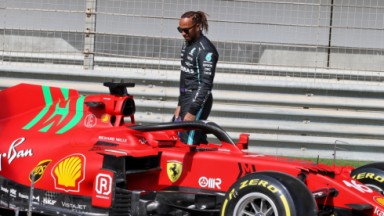 Lewis Hamilton olhando um carro da Ferrari 