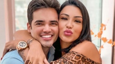 Fábio Gontijo e Jenny Miranda abraçados, posando para foto, ele sorrindo e ela mandando beijo 