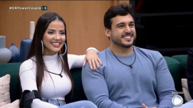 Luana Andrade e João Hadad sorrindo sentados em sofá 