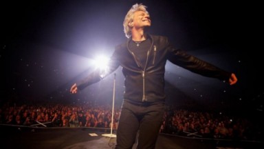 Jon Bon Jovi em registro de show publicado nas redes sociais, vestindo roupa preta 