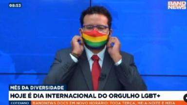 Juliano Dip colocando a máscara da bandeira do arco-íris durante jornal 