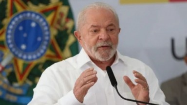 Lula falando em microfone e gesticulando, de camisa social branca 